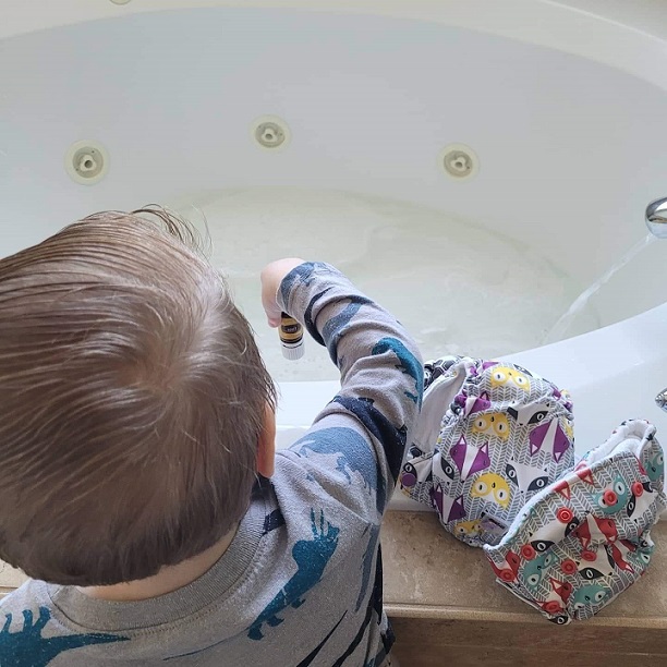 Toddler adding essential oils to a tub for soaking cloth diapers