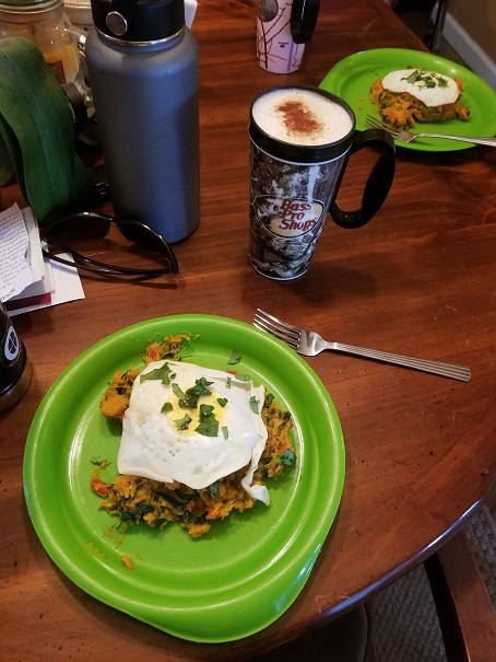 Sautéed sweet potato and kale with a fried egg on top garnished with chopped green onion