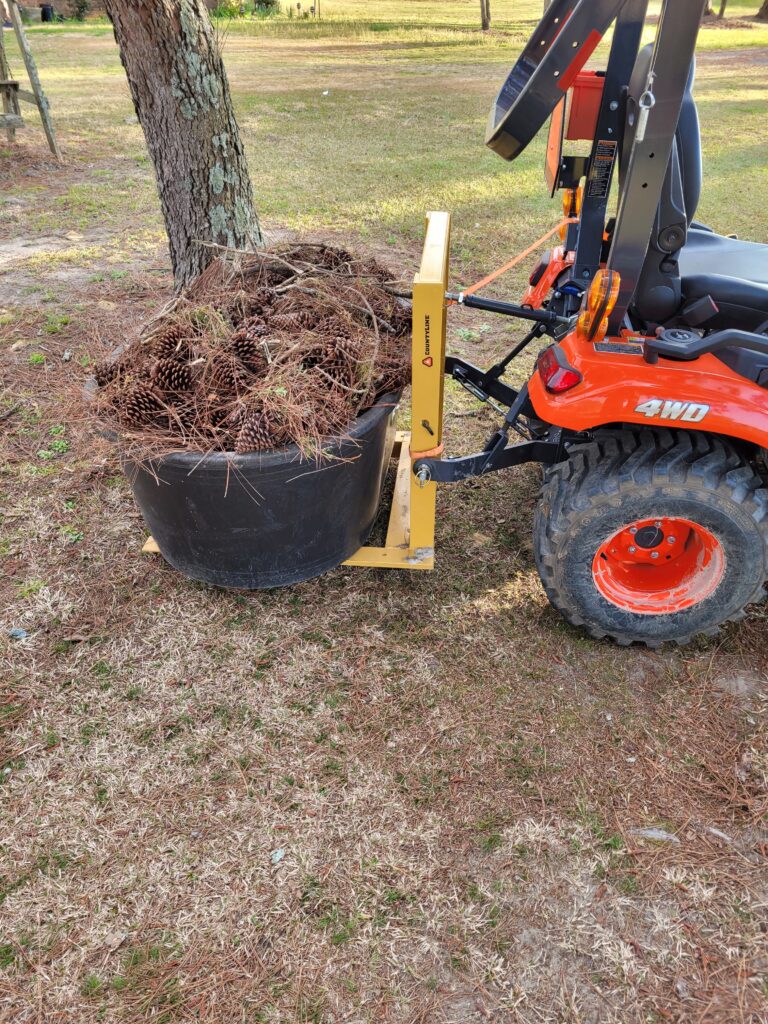 Carry All 3 point attachment on a Kubota Subcompact Tractor with a stock tank loaded with pine shavings