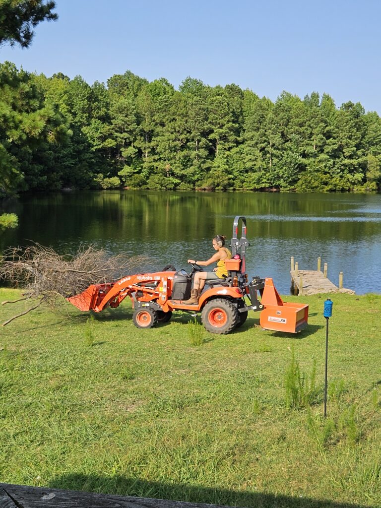 Moving branches to a burn pile using the Kubota subcompact tractor with attached bucket forks