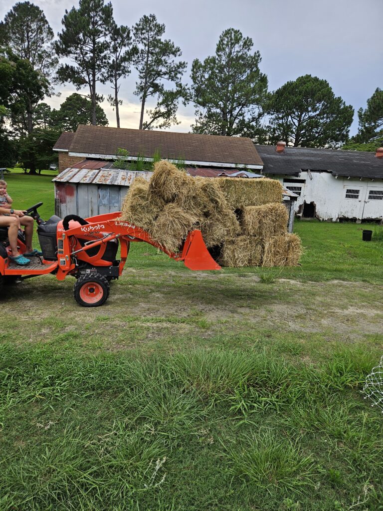 Kubota Tractor with 9 bales of hay on the bucket and forks. 